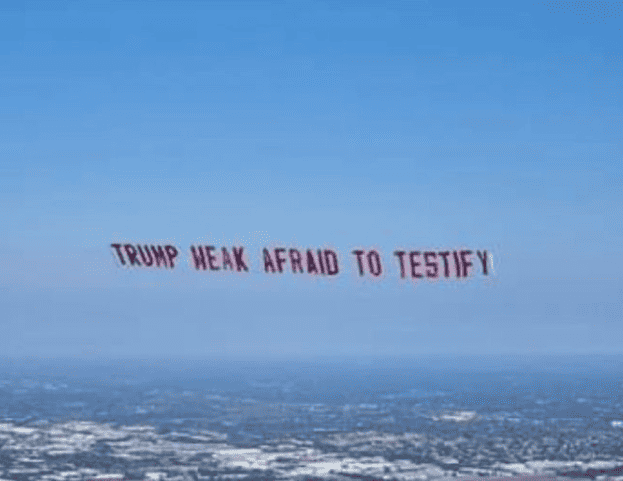 'TRUMP WEAK AFRAID TO TESTIFY' banner flies in Tampa on Super Bowl Sunday.